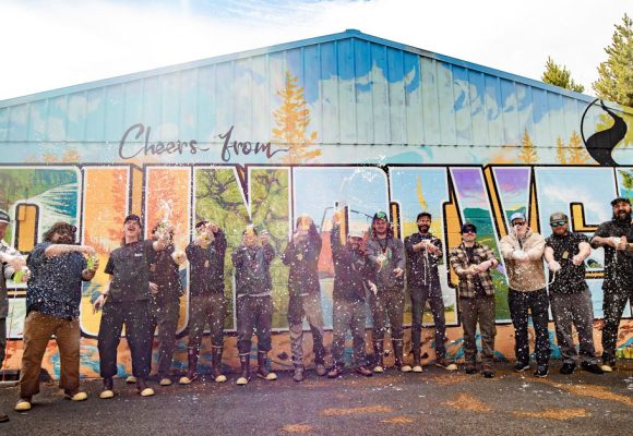 people spraying beverages outside sunriver mural