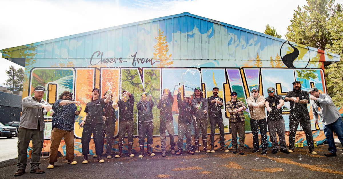 people spraying beverages outside sunriver mural